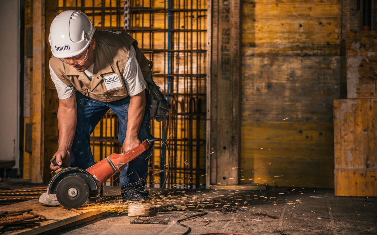 Homme en train de couper une barre de métal sur un chantier d'Enrico Baiutti SA.