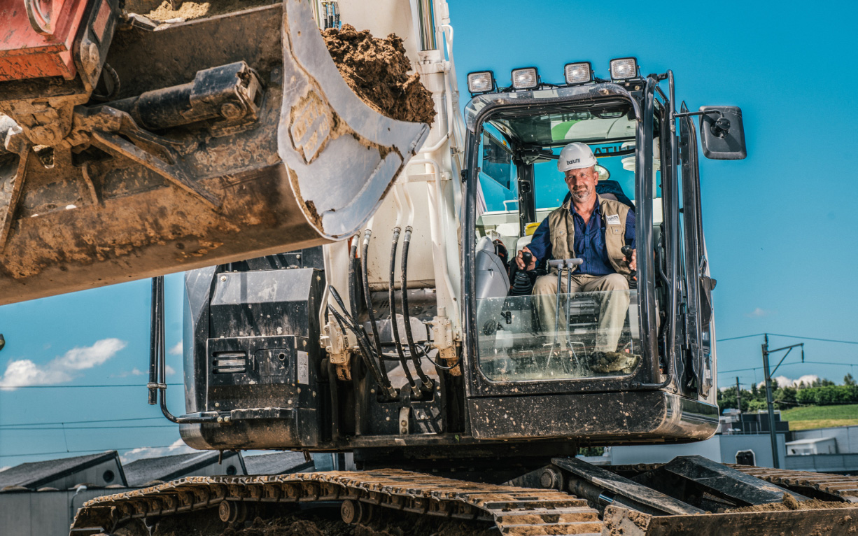 Homme dans un trax en train de travailler la terre sur un chantier d'Enrico Baiutti SA.
